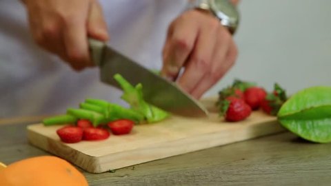 Cutting fruit and vegetable star fruit on a cutting board in the kitchen