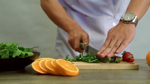 Cutting and chopping fruit and vegetable mint on a cutting board in the kitchen