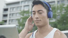 4K Young Asian man in outdoor urban environment makes a video call with headphones and tablet computer. Shot on RED Epic.