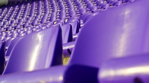 Rows of violet plastic seats on stadium tribune, dolly. COVID-19 quarantine, isolation