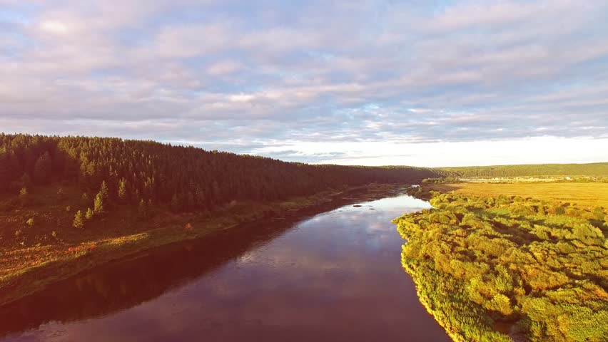 Flight over the river and fields in sun set.