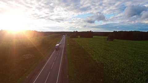 Aerial view of Truck on the road with sunset in the background. Large delivery truck is moving towards setting sun.