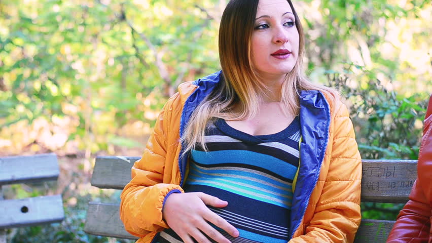 Pregnant girl shows the woman a photo on hers smartphone