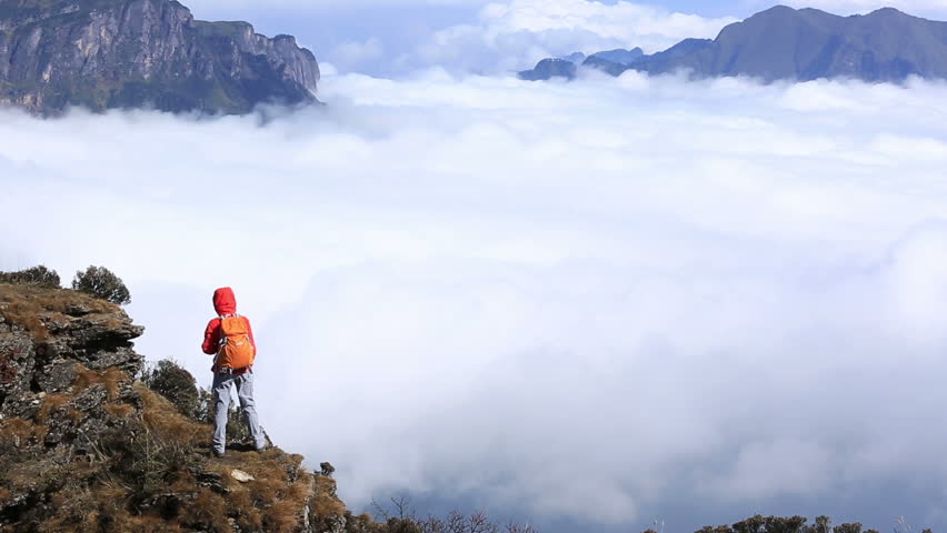 young woman hiker taking photo with smartphone on beautiful mountain peak