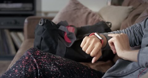 Unrecognizable Sporty woman before gym checking messages on smartwatch at home relaxing on sofa