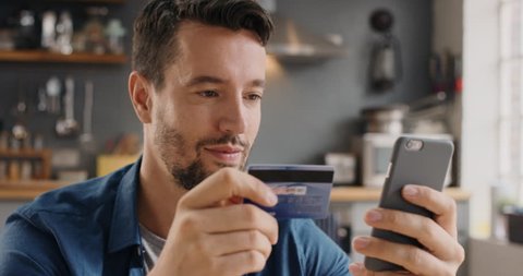 Man shopping online with credit card using smartphone at home lifestyle excited and happy about purchase connected banking mobile app