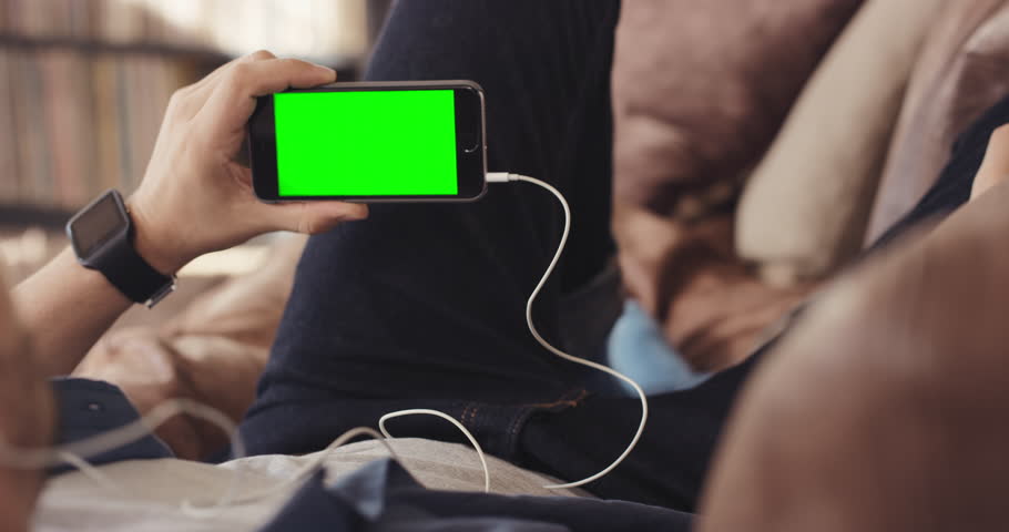 Unrecognizable Cool guy relaxing watching green-screen video movie on couch at home using smartphone listening earphones Royalty-Free Stock Footage #12266297