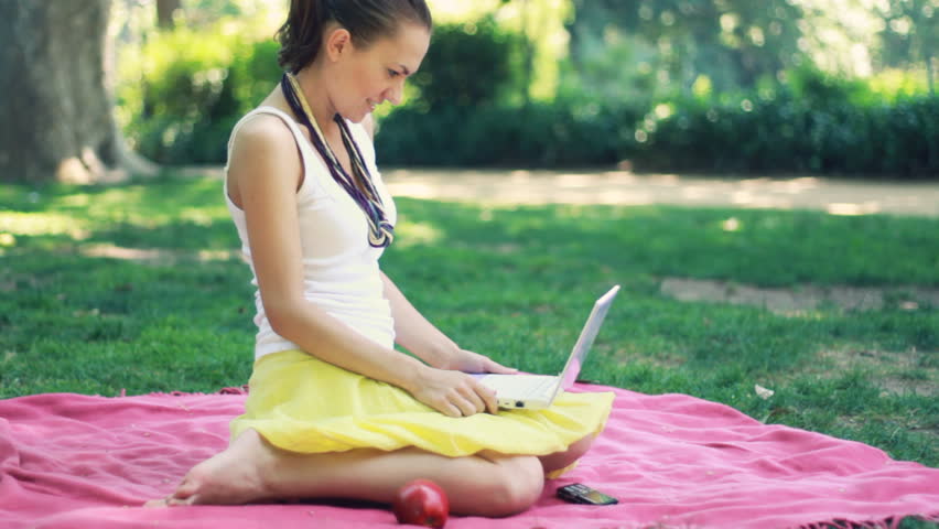 Young woman chatting on laptop in the park 