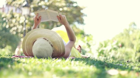 Young woman reading book in park, dolly shot 