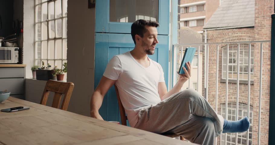 Good looking man at home drinking coffee using digital tablet happy loft apartment in pajamas Royalty-Free Stock Footage #12270119