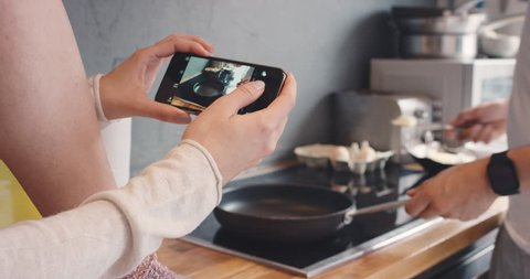 Close crop of happy couple Taking photo using smartphone of breakfast cooking pan butter for social media lifestyle at home in kitchen: stockvideo