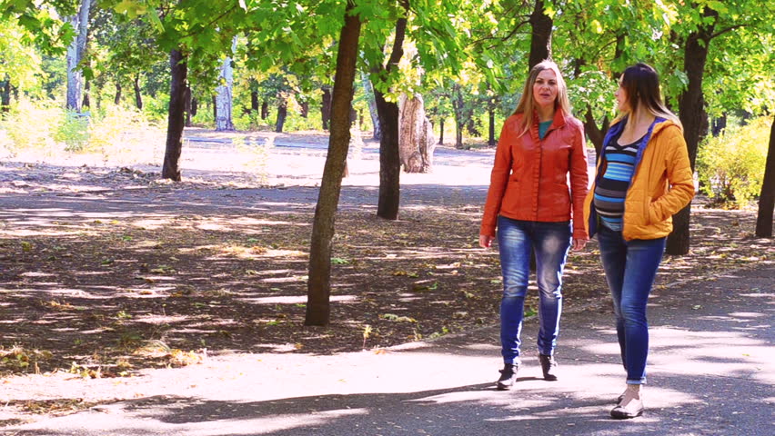 A pregnant woman walks with her sister in the Park through the alley