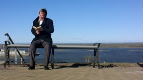 two men sitting outdoors on a bench with a book. Professional shot on BMCC with high dynamic range. You can use it e.g in your commercial video, business or office video, reporting, presentation
