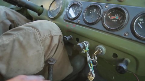 Grandfather starts a retro car. Old military vehicle. Dashboard of an old car.