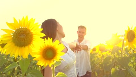 Happy couple running on sunflower field, taking hands and smiling. Happy Young man and woman having fun outdoors. Excited with the freedom of the countryside. Slow motion 1080p. High speed camera 