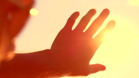 Human hand touching the sunlight by hand over beautiful sky background. Happy man looking at shining sun through his fingers. Slow motion video footage high speed camera 240 fps slowmo, full HD 1080p 