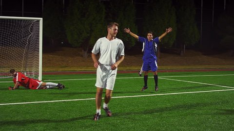 The camera follows a soccer player down the field as he makes a goal