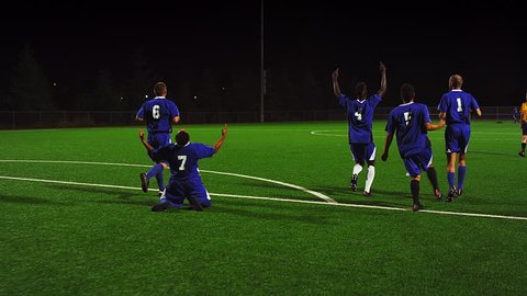 A soccer team runs down the field in celebration