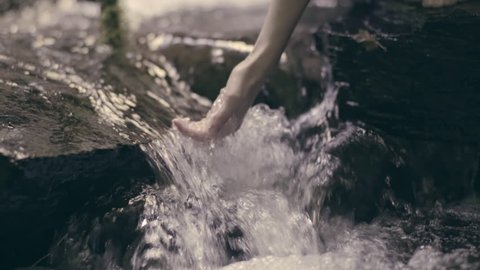 Young Woman Kneels Down In Stream, Scoops Up Water With Her Hand (Slow Motion)