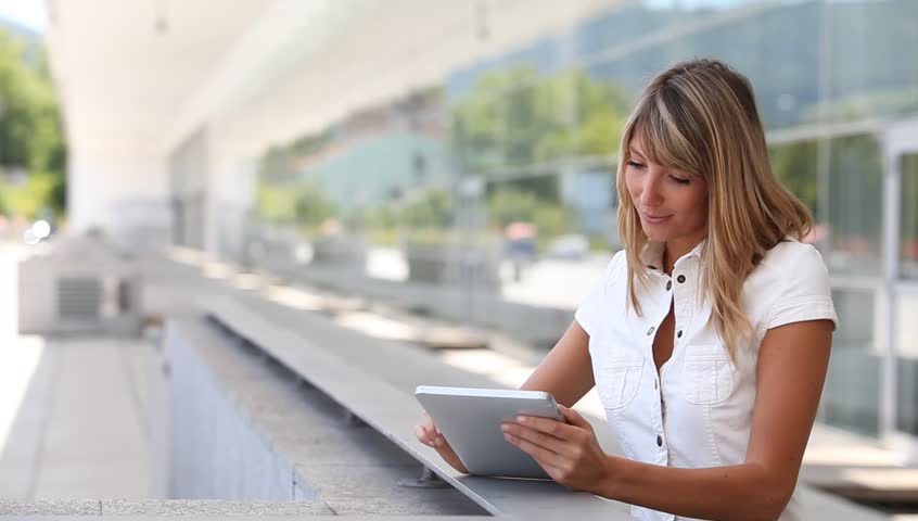 Blond woman using electronic tablet in town