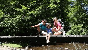 Family sitting on bridge over mountain river