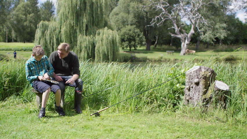 4K Man and young boy together on fishing trip, putting fishing flies on the hook. Shot on RED Epic.