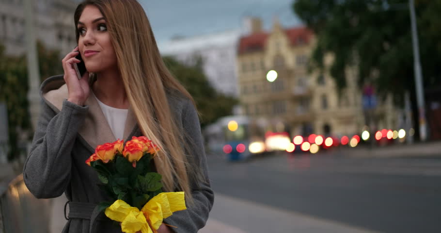 woman sniffing flowers while speaking over the phone, valentines day concept