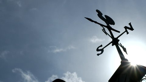 Wind Vane silhouette against a backdrop of moving clouds in the sky