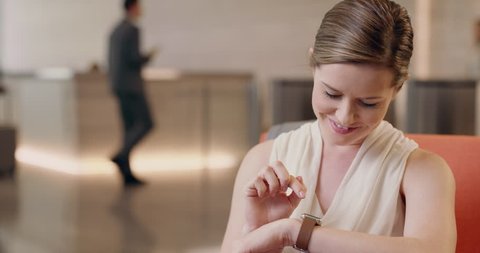 Caucasian businesswoman using smart watch in business reception touching touch screen connecting with sharing app