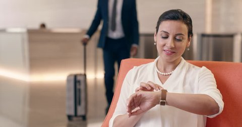 Mixed Race businesswoman using smart watch technology in business lobby touching touch screen connecting with sharing app