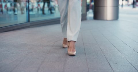 Smart business woman feet close crop walking to work entering glass corporate building wearing high heels urban city commuter concept