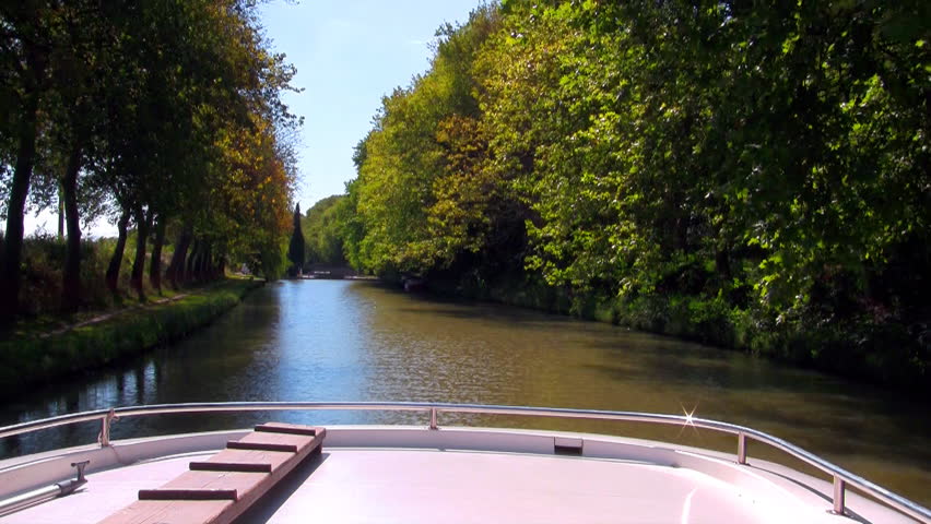 boat floats on the channel under the trees on a sunny day