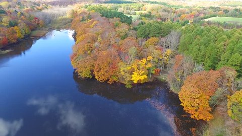 Aerial: Taking surrounded by fall foliage pond in multirotor _
/ October 21, 2015 to the shooting in Japan of Forest Park /
Autumn leaves and pond blue sky and clouds bleeds through.