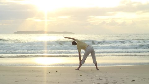 HD 1080i: Young woman doing yoga on the beach at sunrise in Bombinhas - Brazil. Tripod.