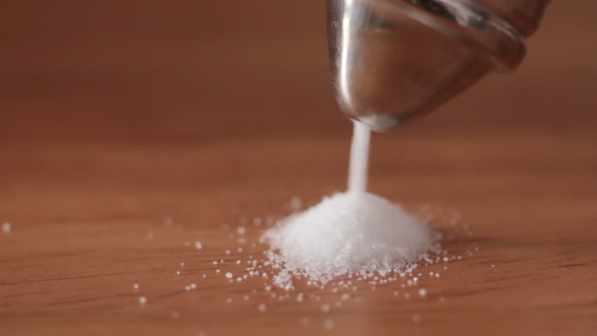 Close up of salt pouring onto wooden table