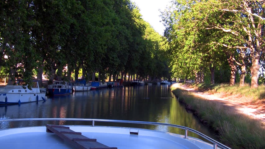 boat floats on the channel under the trees on a sunny day