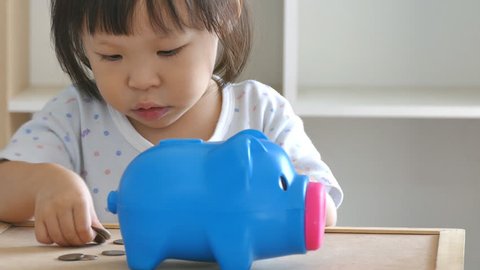 Cute little girl putting money in piggy bank