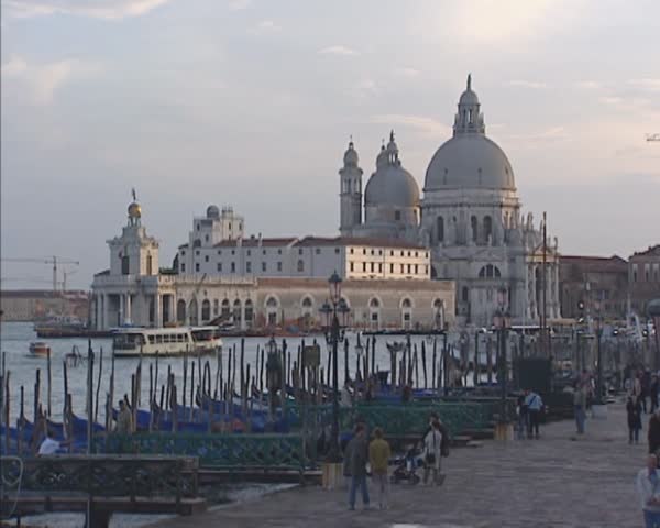 VENICE, ITALY - MAY 2009: Evening skyline Venice Customs House and Santa Maria della Salute. Gondolas moored. Vaporetto bus boat navigates upstream Grand Canal. | Shutterstock HD Video #12363911