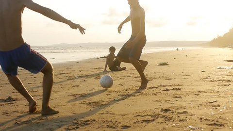 Phan Thiet, Vietnam, October 7: Playing football children on beach at sunset on sea and sky background with back light sun. Kids enjoy sport on sand in slow motion. Vietnam 2015, october.
