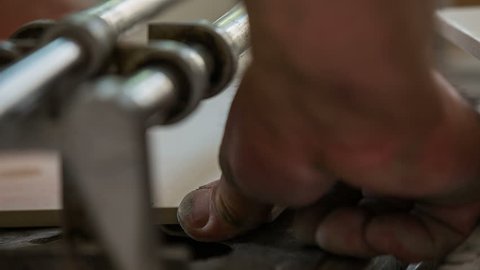 Cutting ceramic tile close up. Person placing a big ceramic tile in a cutter and driver over a blade to cut of excessive material.