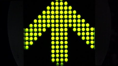 Green LED light arrow pointing up and moving fast upwards large arrow exists of 120 smaller LED lamps all moving by blinking turning on turning off black dark background fast moving lights up signal