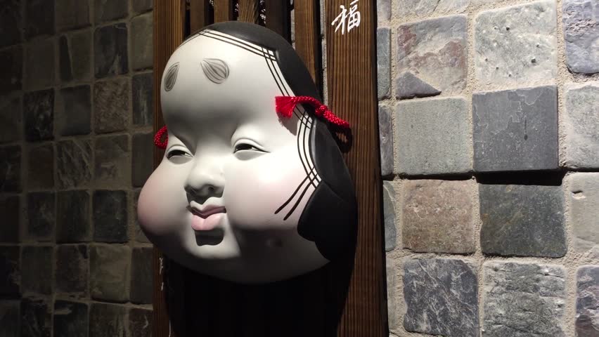 Traditional antique Japanese mask hanging on display on a brick wall