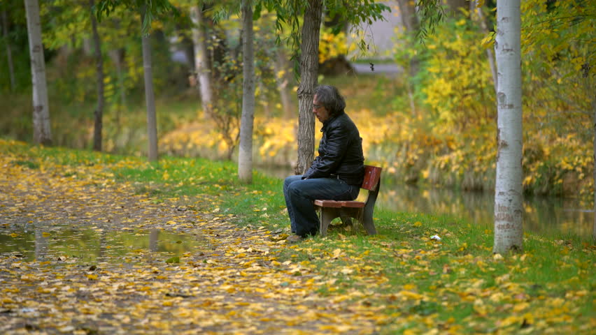 man smoking on a bench in autumn