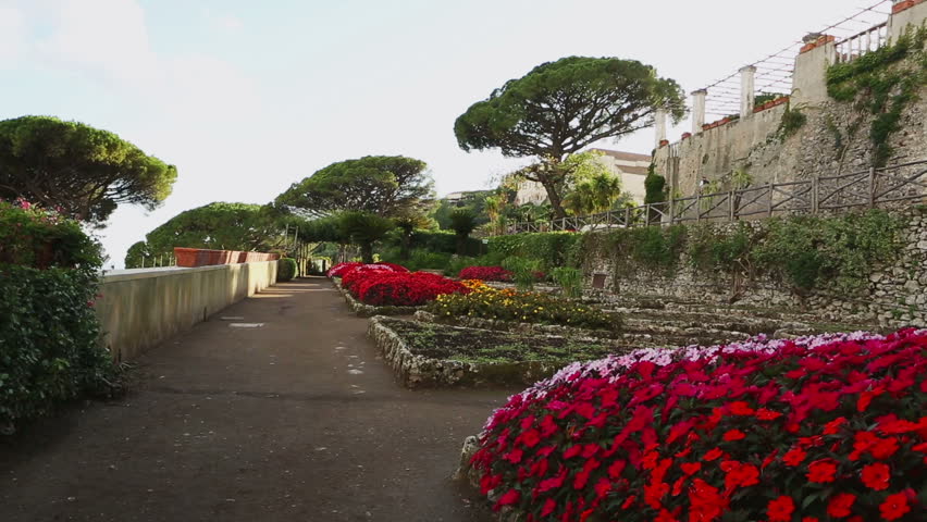 Man with dog walking in romantic flower garden, Villa Rufolo, Ravello, Amalfi coast, Italy, Europe. Video footage. The guy and the dog leave away from the camera