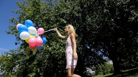 Young woman cheerfully spinning with colorful balloons