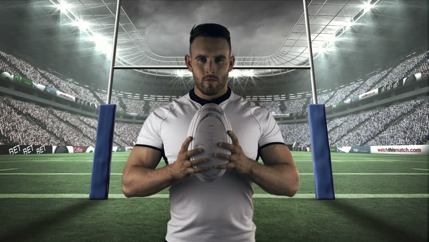 Serious rugby player holding rugby ball in stadium