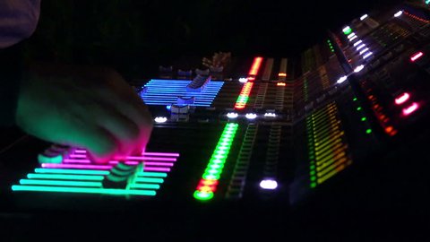 Audio engineer mixing at live performance concert on professional music mixete lit at night