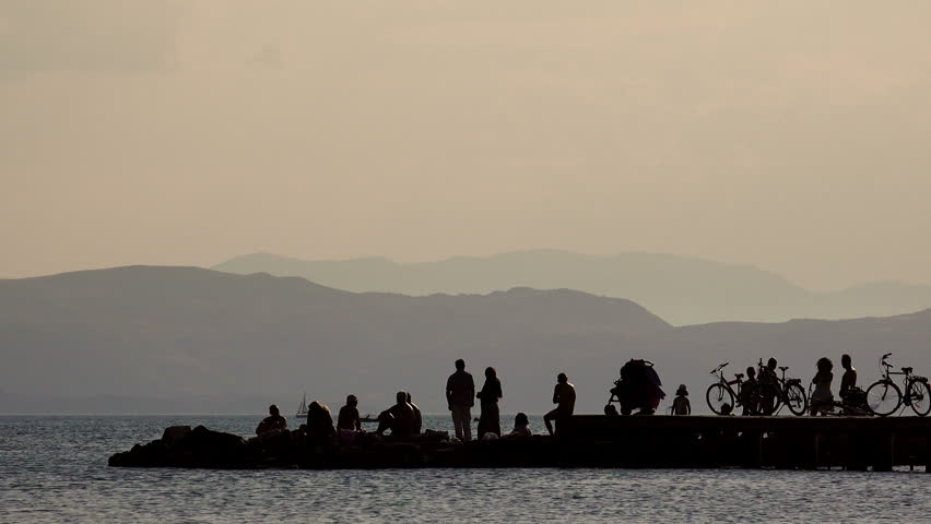 Silhouettes tourists on the Pier at Sunset Closeup