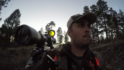 A hunter walks quietly through a forrest hunting deer with his rifle