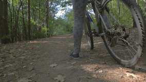 Woman starting to ride a bike through a green forest / slowmotion / video from the ground